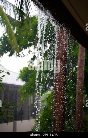 Wasser fällt vom Dach und bricht den Abfluss während eines schweren tropischen Regenfalls. Stockfoto