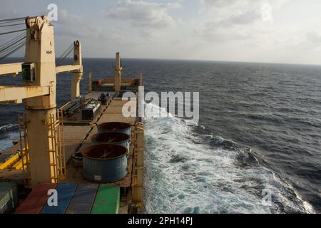 Ein normales Frachtschiff mit schweren Kranen ist bei ruhigem Wetter auf See unterwegs Stockfoto