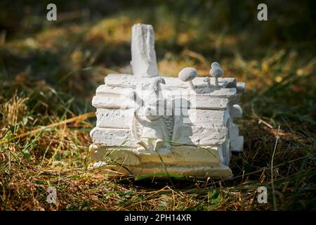 Kleine Igelstatue, die in Holzholz sitzt und ein Teleskop am Sternenhimmel betrachtet, mit grünem Gras Hintergrund, niedliche Kinder, die Igelfigur hergestellt aus fr Stockfoto