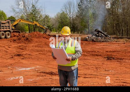 Bauingenieur mit umfassender Erfahrung in der Sicherheitsüberwachung des Baufortschritts, während er die Baupläne in der Hand hält. Stockfoto