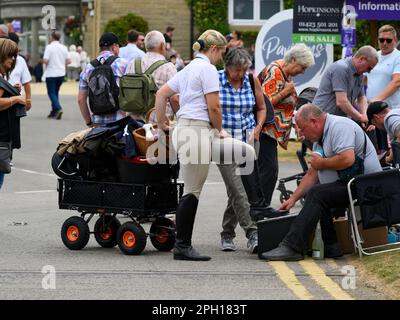 Schuhputzer bei der Arbeit, der Lederstiefel für weibliche Kunden poliert (Polieren, 1 One Foot on Footrest, People) – Great Yorkshire Show, Harrogate, England, Großbritannien. Stockfoto