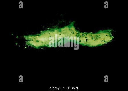 Spliss von Steinrückständen, die mit grünem Pulver auf schwarzem Hintergrund explodieren. Stockfoto
