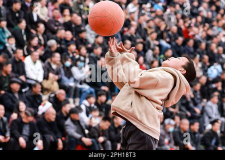 (230325) -- TAIJIANG, 25. März 2023 (Xinhua) -- Ein Kind spielt Basketball in Taipan Village, Taijiang County, Guizhou Province im Südwesten Chinas, 25. März 2023. „Village Basketball Association“ oder „Village BA“ ist ein Basketballturnier mit Grassroot im Dorf Taipan. Diese von Einheimischen organisierte Veranstaltung hat im Laufe der Jahre an Popularität gewonnen und zieht eine große Menge von Zuschauern und Teilnehmern gleichermaßen an. Das Turnier zeigt die Leidenschaft und das Können von Basketballspielern aus ländlichen Gebieten, während sie auf dem Platz gegeneinander antreten und ihre Teamarbeit demonstrieren. (Xinhua/Ou Dongqu) Stockfoto