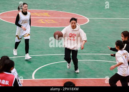 (230325) -- TAIJIANG, 25. März 2023 (Xinhua) -- Teenager spielen Basketball in Taipan Village, Taijiang County, Guizhou Province im Südwesten Chinas, 25. März 2023. „Village Basketball Association“ oder „Village BA“ ist ein Basketballturnier mit Grassroot im Dorf Taipan. Diese von Einheimischen organisierte Veranstaltung hat im Laufe der Jahre an Popularität gewonnen und zieht eine große Menge von Zuschauern und Teilnehmern gleichermaßen an. Das Turnier zeigt die Leidenschaft und das Können von Basketballspielern aus ländlichen Gebieten, während sie auf dem Platz gegeneinander antreten und ihre Teamarbeit demonstrieren. (Xinhua/Ou Dongqu) Stockfoto