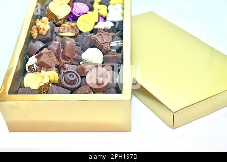 Goldene Schachtel mit verschiedenen handgemachten Pralinen Bonbons auf weißem Hintergrund Stockfoto