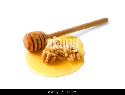 Mehrere Walnüsse und ein hölzerner Dipper liegen in einem Tropfen Honig auf weißem Hintergrund. Große Walnüsse und Honig isoliert auf weißem Hintergrund. Stockfoto