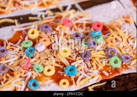 Pizza von einem Kind mit Müsli, Käse und Sauce. Stockfoto