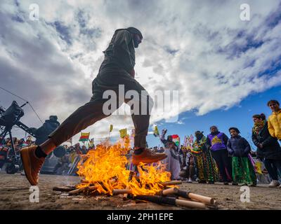 25. März 2023, Hessen, Frankfurt/Main: Bei der zentralen Feier des kurdischen Neujahrs "Newroz" springt ein Mann über ein Feuer. Tausende von Menschen aus ganz Deutschland haben sich im Rebstockpark versammelt, um das kurdische Neujahr „Newroz“ zu feiern. Foto: Andreas Arnold/dpa Stockfoto