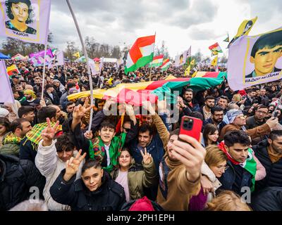 25. März 2023, Hessen, Frankfurt/Main: Die Menschen nehmen an der zentralen Feier des kurdischen Neujahrs "Newroz" Teil und schwenken mit Fahnen. Tausende von Menschen aus ganz Deutschland haben sich im Rebstockpark versammelt, um das kurdische Neujahr „Newroz“ zu feiern. Foto: Andreas Arnold/dpa Stockfoto
