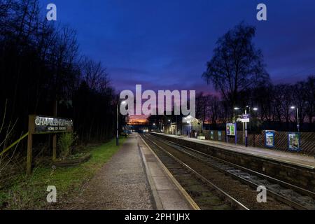 Northern Rail Klasse 150 DMU Zug, Ankunft am kleinen 2 Bahnsteig Chapel-en-Le-Frith Bahnhof, Derbyshire in der Dämmerung mit einem roten Sonnenuntergang Stockfoto