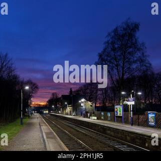 Northern Rail Klasse 150 DMU Zug, Ankunft am kleinen 2 Bahnsteig Chapel-en-Le-Frith Bahnhof, Derbyshire in der Dämmerung mit einem roten Sonnenuntergang Stockfoto