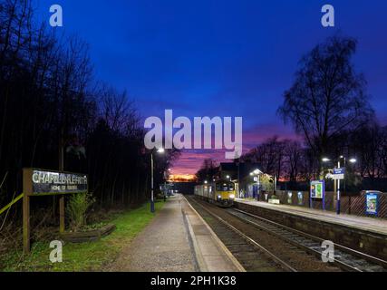 Der Zug der Northern Rail Klasse 150 DMU fährt zum kleinen Bahnhof Chapel-en-Le-Frith, Derbyshire, mit 2 Bahnhöfen und rotem Sonnenuntergang Stockfoto