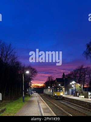 Der Zug der Northern Rail Klasse 150 DMU fährt zum kleinen Bahnhof Chapel-en-Le-Frith, Derbyshire, mit 2 Bahnhöfen und rotem Sonnenuntergang Stockfoto