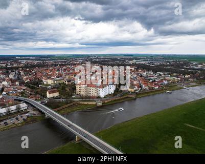 torgau mit einem wolkigen Himmel. Regenwolken über der Stadt. elbe und elbbrücke im Vordergrund. Altstadt und Umgebung im Hintergrund Stockfoto