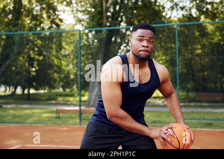 Ein afroamerikanischer Mann spielt Basketball auf dem Platz im Freien Stockfoto