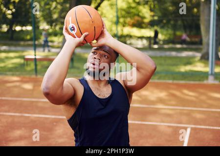 Ein afroamerikanischer Mann spielt Basketball auf dem Platz im Freien Stockfoto