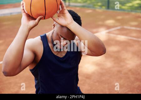Ein afroamerikanischer Mann spielt Basketball auf dem Platz im Freien Stockfoto