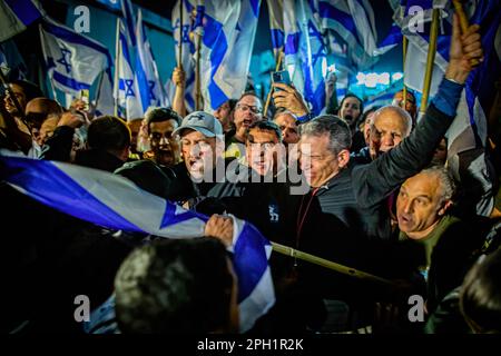 Israelische Demonstranten winken Flaggen, während sie von Polizeibeamten während eines Protests gegen die Justizreform zurückgedrängt werden. Der israelische Ministerpräsident Benjamin Netanjahu schwor am Donnerstag, die Kluft in einer Nation zu beseitigen, die über seine geplante Generalüberholung der Justiz tief gespalten war. Netanjahu legte seine Berufung in einer landesweit im Fernsehen übertragenen Ansprache nach einem weiteren Tag Massenproteste gegen den Plan im ganzen Land ab. Seine vagen Versprechen wurden von der Protestbewegung, die sagte, sie würde sich weiterhin gegen Netanjahus Versuch, ein Diktator zu werden, stellen. Stockfoto