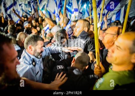 Israelische Demonstranten winken Flaggen, während sie von Polizeibeamten während eines Protests gegen die Justizreform zurückgedrängt werden. Der israelische Ministerpräsident Benjamin Netanjahu schwor am Donnerstag, die Kluft in einer Nation zu beseitigen, die über seine geplante Generalüberholung der Justiz tief gespalten war. Netanjahu legte seine Berufung in einer landesweit im Fernsehen übertragenen Ansprache nach einem weiteren Tag Massenproteste gegen den Plan im ganzen Land ab. Seine vagen Versprechen wurden von der Protestbewegung, die sagte, sie würde sich weiterhin gegen Netanjahus Versuch, ein Diktator zu werden, stellen. Stockfoto