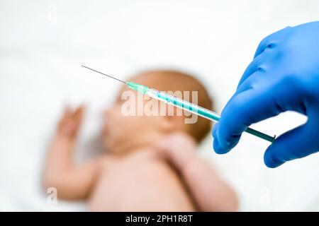 Kinderarzt impft Neugeborenes. Impfstoff, Impfung für Kleinkinder Soft Focus Spritze in die Hände einer Krankenschwester und verschwommener Hintergrund des Säuglings b Stockfoto
