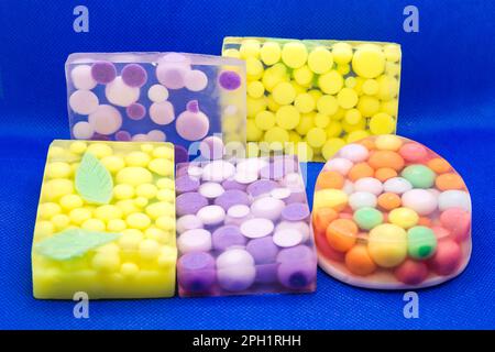 Drei transparente Seifenstücke mit leuchtend bunten Kugeln auf blauem Hintergrund. Stockfoto