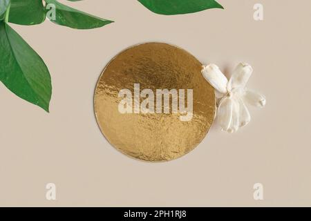 Goldenes rundes Podium auf beigefarbenem Hintergrund für Kosmetik oder Ihr Logo. Goldener Sockel mit trockener Blume. Produkte werden angezeigt. Glänzende Texturoberfläche. Trendiges T Stockfoto