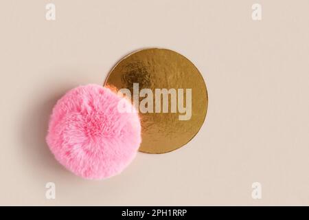 Goldenes rundes Podium auf beigefarbenem Hintergrund für Kosmetik oder Ihr Logo. Goldener Sockel mit pinkfarbenem flauschigem. Produkte werden angezeigt. Glänzende Texturoberfläche. Trendig Stockfoto