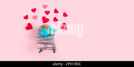 Earth Planet Globe im Supermarkt-Trolley mit roten Herzen auf pinkfarbenem Hintergrund. Valentinstagsangebot. Werbeaktion und Shopping-Vorlage für Love A Stockfoto