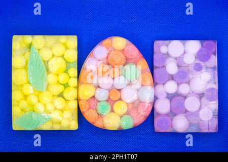 Drei durchsichtige Seifenstücke mit bunten Kugeln auf blauem Hintergrund. Stockfoto