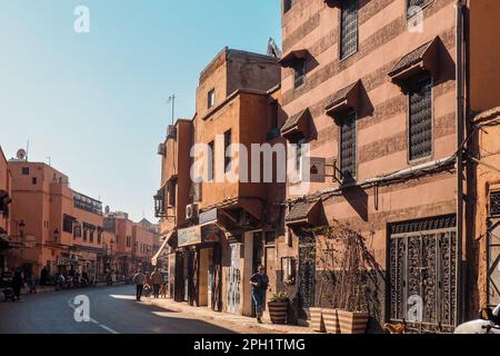 Marrakesch, Marokko - 02. Januar 2020: Menschen, die in einer typisch marokkanischen Stadt spazieren, scheinen in Häuser mit dekorierten Fenstern und Toren, Wände aus Stockfoto