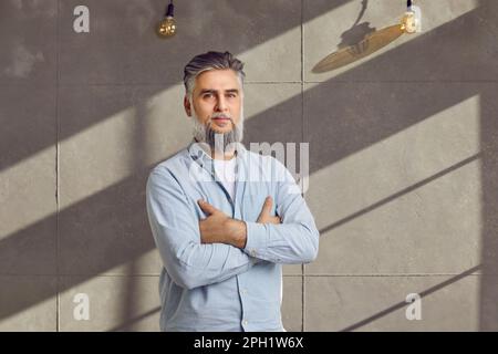 Porträt eines bärtigen Mannes mittleren Alters, der mit gekreuzten Armen steht Stockfoto