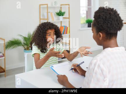 Erstauntes afroamerikanisches Teenager-Mädchen spricht mit Schulpsychologin über ihre Probleme. Stockfoto