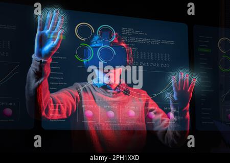 Junger Mann mit VR-Headset, wischte mit Handgesten über futuristische Schnittstellen im Metaversum; Studioaufnahme mit blauen und roten Lichtern. Stockfoto