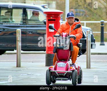 Mann im orangefarbenen Muschelanzug auf einem Roller Stockfoto