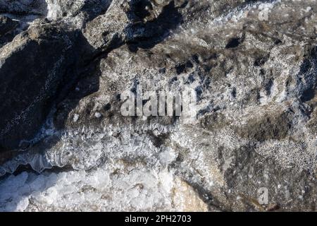 Schwarze Felsen an der Atlantikküste. Kristalle aus Meersalz, die verschiedene Formen von Sedimenten erzeugen. Aguas Verdes, Fuerteventura, Kanarische Inseln, Stockfoto