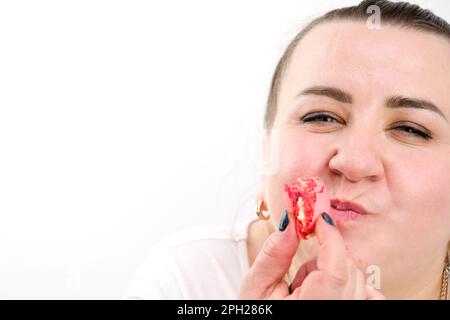 Schönes Modemodel mit roten Lippen beißt bunte Makronen. Nahaufnahme. Glückliche Frau, die französische Makrone isst. Die Frau hält farbenfrohe Makronen. Französisches Dessert. Sweets-Frau beißt Makrone Stockfoto