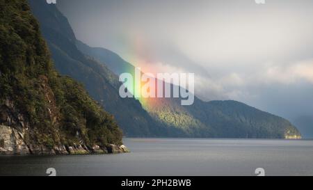 Ein lebendiger Regenbogen leuchtet im Morgenlicht im Doubtful Sound von Neuseeland. Stockfoto