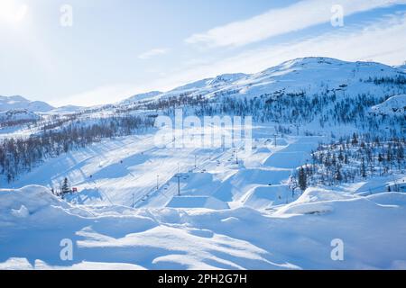 Blick auf das Skigebiet mit Pisten, Sesselliften und majestätischen schneebedeckten Bergen am Wintertag. Stockfoto