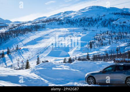 Blick auf das Skigebiet mit Pisten, Sesselliften und majestätischen schneebedeckten Bergen am Wintertag. Stockfoto