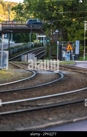 Göteborg, Schweden - Oktober 03 2022: Straßenbahn, die an einer Straßenbahnhaltestelle vorbeifährt und unter einer Brücke hindurch fährt Stockfoto