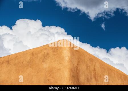 Mit Lehmziegeln verkleidete Wände eines Gebäudes in Taos New Mexico in Schuss vor einem blauen Himmel mit flauschigen Cumulus-Wolken Stockfoto