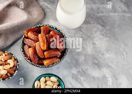 Ramadan Kareem – Speisen und Getränke. Getrocknete Datteln, Nüsse und Milch auf grauem Hintergrund. Islamische Religion und ramadan-Konzept. Draufsicht. Speicherplatz kopieren Stockfoto