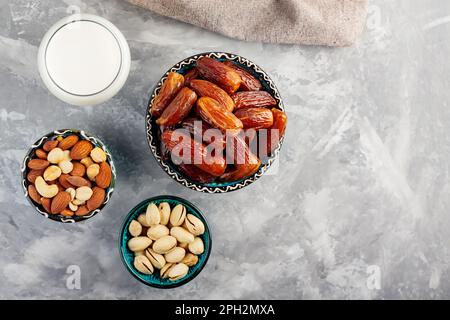 Ramadan Kareem – Speisen und Getränke. Getrocknete Datteln, Nüsse und Milch auf grauem Hintergrund. Islamische Religion und ramadan-Konzept. Draufsicht. Speicherplatz kopieren Stockfoto