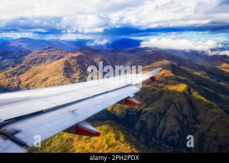 Ein Passenter-Flugzeug in der Luft, das über malerische Berge rund um Queenstown in Neuseeland fliegt. Stockfoto