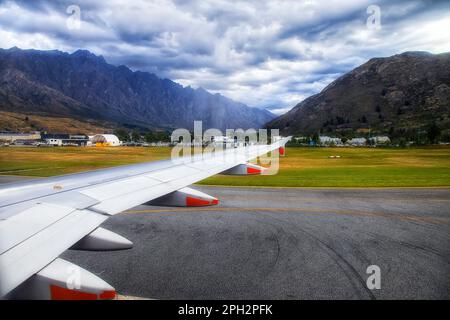 Passagierflugzeug auf der Landebahn des Flughafens Queenstown, umgeben von malerischen Bergen - beliebtes Reiseziel in Neuseeland. Stockfoto