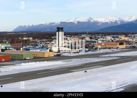 Merrill Field Airport in Anchorage und seine Flugverkehrskontrolle (ATC Tower), die hauptsächlich für die allgemeine Luftfahrt genutzt wird. Merrill Field mit Bergen dahinter. Stockfoto