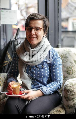 Ein Mädchen, das in einem Café sitzt und aufpasst Stockfoto