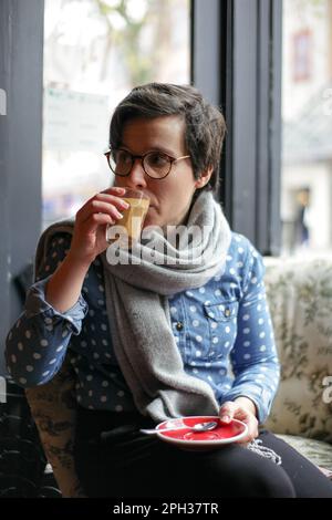 Ein Mädchen, das in einem Café sitzt und aufpasst Stockfoto