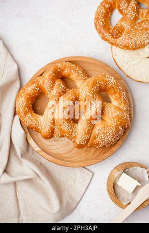 Teller mit leckeren Brezeln und Butter auf hellem Hintergrund Stockfoto