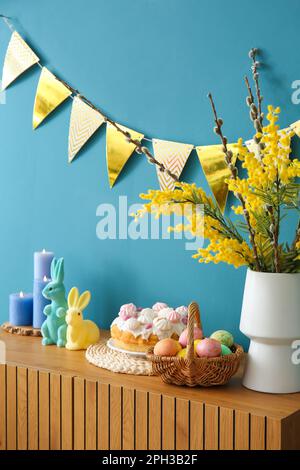 Osterdekorationen auf einem Holzschrank in der Nähe der blauen Wand Stockfoto